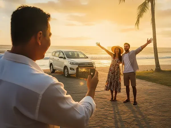 sopir yang sedang foto sepasang tamu wisatawan di pinggir pantai ada sunsetnya
